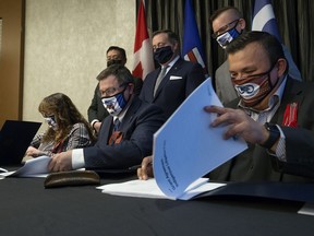 Premier Jason Kenney (back centre) watches as (left to right) Willow Lake Métis Nation president Stella Lavalee, Indigenous Relations Minister Rick Wilson, and Fort McKay Métis Nation president Ron Quintal sign an agreement that will see the Alberta Government provide a $372,000 grant to support the two Métis organizations in their fight against Bill C-48, in Edmonton Monday Nov. 15, 2021.