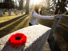 Grade 8 Jean Forest Leadership Academy student Somara Gouda places a poppy on a gravestone as she takes part in the 11th annual Remembrance ceremony for 'No Stone Left Alone' at Beechmount Cemetery, 12420 104 St., in Edmonton, Thursday Nov. 4, 2021.