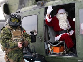 Santa played by Master Warrant Officer Mark Riley waves prior to departing for the Stollery Children's Hospital to deliver presents by flying on a Royal Canadian Airforce CH-146 Griffon Helicopter, Tuesday, Dec. 14, 2020.