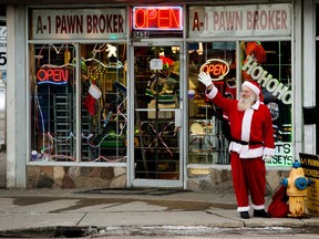 Dressed as Santa Clause, Doug Hoy waves to passersby outside A1 Pawn Edmonton, 9434 111 Ave., Saturday Dec. 11, 2021. Hoy's son owns the store, and Hoy says he dresses up as Santa outside the store every year. Photo by David Bloom