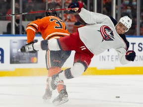 Edmonton Oilers’ Warren Foegele (37) hits Columbus Blue Jackets’ Max Domi (16) at Rogers Place in Edmonton on Thursday, Dec. 16, 2021.