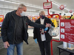 Shopper Bob Hoskins makes a donation to the Salvation Army Kettle Campaign at Capilano Walmart on December 6, 2021, where  Kettle Campaign volunteer Cheryl Onciul was stationed. The annual Christmas Kettle Campaign needs 1500 volunteer shifts filled between now and Christmas Eve to reach their $600,000 goal. Each Kettle needs a volunteer attendant and with so many empty shifts, that means some Kettles won't be set out to collect donations.