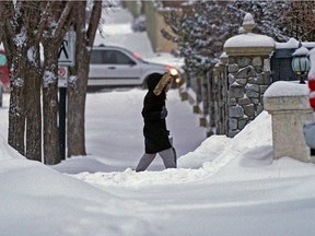 A pedestrian walks on a residential street in southwest Edmonton on Tuesday December 14, 2021. A heavy snowfall warning has been issued for region with total amounts of 10 to 20 cm. expected throughout the day.