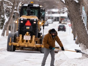 Kevin Wirtanen enthusiastically clears a parking spot in front of his home after graders with the City of Edmonton complete residential snow clearing in the Parkallen neighbourhood of Edmonton on Tuesday, Dec. 21, 2021. Wirtanen said he's pleased with the service the city gives when clearing residential streets.