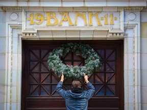 Teatro Restauant's Lyndon Strandquist adds a Christmas wreath above the restaurant entrance in the historic 1911 bank building in downtown Calgary on Thursday, November 25, 2021.