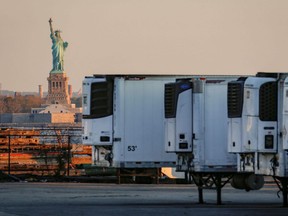 Refrigerated tractor trailers used to store bodies of deceased people are seen at a temporary morgue, with the Statue of Liberty in the background, during the COVID-19 outbreak, in the Brooklyn borough of New York City, on May 13, 2020.