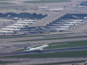 In this file photo taken on April 24, 2020 Cathay Pacific passenger airplanes are seen parked on the tarmac as a Cathay Pacific Cargo plane (bottom) takes off at Hong Kongs Chek Lap Kok International Airport in Hong Kong.
