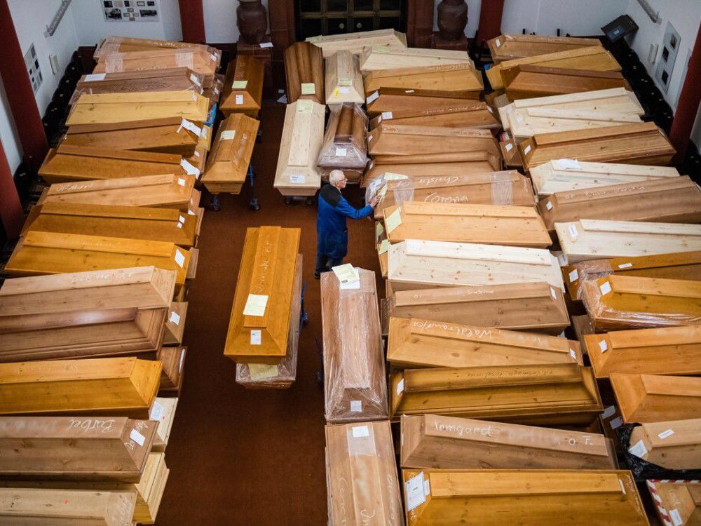  An employee moves coffins, some marked with “infection risk” as others have “corona” scrawled in chalk, in the mourning hall of the crematorium in Meissen, eastern Germany, on January 13, 2021, amid the new coronavirus COVID-19 pandemic.