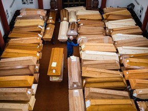 An employee moves coffins, some marked with "infection risk" as others have "corona" scrawled in chalk, in the mourning hall of the crematorium in Meissen, eastern Germany, on January 13, 2021, amid the new coronavirus COVID-19 pandemic.