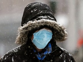 A pedestrian walks in downtown Edmonton during a snowfall on Wednesday December 22, 2021.