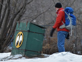 A pedestrian walks by a city-supplied sandbox.