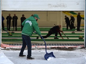 Shovel hard. Ice maker Dave Nickless clears the snow by the loading dock door which is a 1/3 open showing the curlers playing inside the Granite Curling Club in Edmonton, December 2, 2021. Ed Kaiser/Postmedia