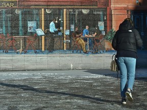 Miss the days of sitting outside at a eatery as this wall mural depicits, as a pedestrian in a winter coat walks past along 124 St. as cold weather made its appearance on the weekend in Edmonton, December 6, 2021. Ed Kaiser/Postmedia