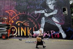 I just like the face they are making as they sneak past the camera. A pedestrian walks past a mural being painted in honour of Ken “Mr. Chi Pig” Chinn, lead vocalist of punk band SNFU on June 22, 2021. The approximately 2,600-square-foot mural was being painted on the east side of The Buckingham, 10439 82 Ave.