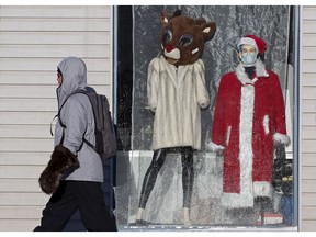 A pedestrian walks past a Christmas themed window display at the Bissell Thrift Shop, 8818 118 Ave., in Edmonton Friday Dec. 17, 2021. Photo by David Bloom