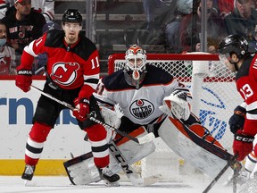 Mike Smith (41) of the Edmonton Oilers and Andreas Johnsson (11) of the New Jersey Devils keep their eyes on the puck at Prudential Center on Dec. 31, 2021, in Newark, New Jersey.