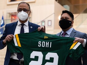 Edmonton Mayor Amarjeet Sohi (left) receives an Elks jersey from new Elks president and CEO Victor Cui at City Hall on Tuesday, Jan. 25, 2022.