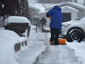 More shovelling was the order of the day as snow fell again while two people work at clearing the sidewalk in southwest Edmonton, January 7, 2022.