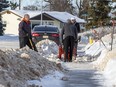 Neighbours Dana Sydor, Isa  Khurshed, and Nizam Khurshed clear the windrows from in font of their homes shortly after a grader had created them on Wednesday, Jan. 12, 2022 in north Edmonton.