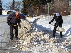 Neighbours Dana Sydor and Nizam Khurshed  clear the windrows from in front of their homes shortly after a grader had created them on Wednesday, Jan. 12, 2022 in north Edmonton.