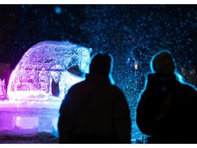 Visitors take photos with an ice sculpture by Barry Collier during the Deep Freeze A Byzantine Winter Fete at Borden Park as snow falls in Edmonton, on Friday, Jan. 21, 2022.