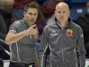 Skip Kevin Koe of Calgary, right, and second John Morris review their options against team Brendan Bottcher during the Tim Hortons Curling Trials in Saskatoon on Nov. 24, 2021.