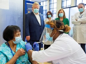 Premier Doug Ford and Minister of Health Christine Elliott watch as a healthcare worker administers the second dose of the Pfizer-BioNTech vaccine to personal support worker Anita Quidangen, who is the first person in Ontario to receive both doses, on January 4, 2021.