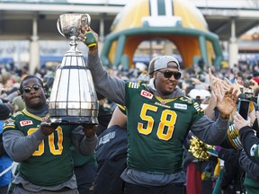 Edmonton Elks Almondo Sewell (90) and Tony Washington (58) carry the Grey Cup into a Grey Cup rally at Churchill Square in Edmonton on Dec. 1, 2015.