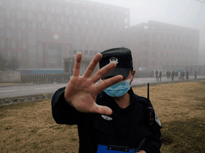 A security guard moves journalists away from the Wuhan Institute of Virology after a World Health Organization team arrived for a field visit, February 3, 2021.