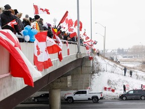 Supporters of a convoy of truckers driving from British Columbia to Ottawa in protest of a Covid-19 vaccine mandate for cross-border truckers gather near a highway overpass outside of Toronto, Ontario, Canada, January, 27, 2022. - A convoy of truckers started off from Vancouver on January 23, 2022 on its way to protest against the mandate in the capital city of Ottawa. (Photo by Cole Burston / AFP)