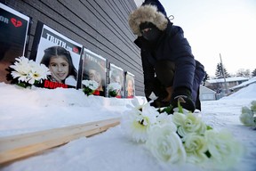 Nargef Jamali lays flowers in front of photos of Edmontonians who were killed when Ukraine International Airlines Flight PS752 was shot down, during a vigil to mark the the second anniversary of the incident, in Edmonton on Saturday, Jan. 8, 2022. Thirteen Edmontonians were killed in the incident.