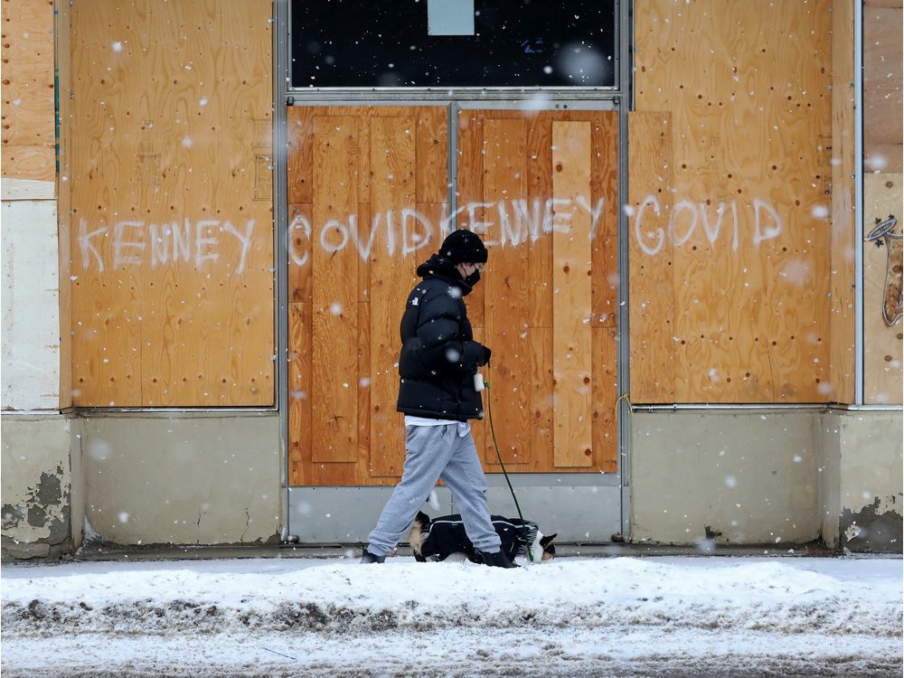  A person walks their dog past graffiti on a boarded up building near 103 Avenue and 106 Street, in Edmonton on Wednesday, Jan. 26, 2022.