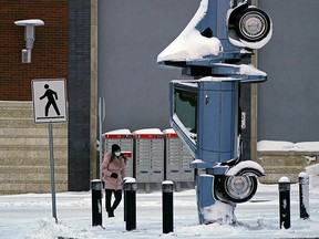 A woman walks past a snow-covered car at a pedestrian crossing in Edmonton on Wednesday January 5, 2022. An extreme cold warning issued for the Edmonton region brought temperatures of -30C degrees and wind chill values of -40C degrees to the city, along with icy road conditions. The car is an art installation at Unity Square shopping centre. (PHOTO BY LARRY WONG/POSTMEDIA)