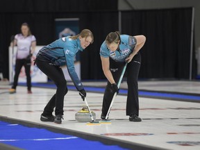 Jessie Haughian, left, and Kristie Moore of Casey Scheidegger's rink sweep a rock at the 2022 Sentinel Storage Alberta Scotties Tournament of Hearts in Grande Prairie.