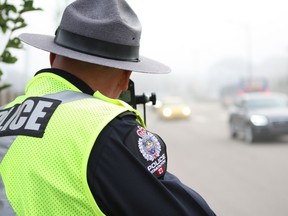 A traffic enforcement officer with the Edmonton Police Service's Southwest Division, looks through a  radar gun outside of St. John XXIII Catholic Elementary/Junior High School at 365 Windermere Road. File photo.