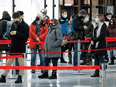 People wait in line at a COVID-19 vaccination centre inside the Olympic Stadium in Montreal, on January 13, 2022. Evidence is showing that vaccine mandates — designed in large part to make public gatherings safer — also spur people to get vaccinated.