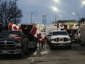 Protesters with trucks and other vehicles adorned in signs and Canadian flags gather Ambassador Bridge on Wednesday. Protesters have shut down the bridge between Detroit and Windsor since Monday. Each day it's closed costs $450 million to the economies of Canada and the U.S.
