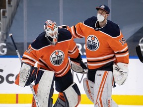 Mikko Koskinen (19) congratulates fellow Edmonton Oilers goaltender Mike Smith (41) after the team beat the Ottawa Senators 7-1 at Rogers Place in Edmonton on March 10, 2021.