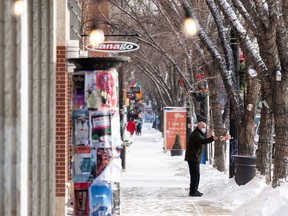 A man uses a waste bin as the temperature hit -18 degrees Celcius along Whyte Avenue in Edmonton, on Thursday, Feb. 3, 2022.