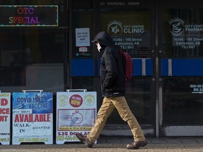 A pedestrian walks past advertisements for COVID-19 vaccinations and rapid testing at the City Centre Clinic,10264 100 St., in Edmonton on Monday, Feb. 7, 2022.