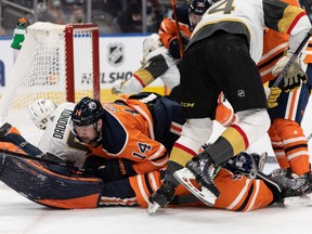 Edmonton Oilers’ Devin Shore (14) lands on goaltender Mike Smith (41) as they play the Las Vegas Golden Knights during second period NHL action at Rogers Place in Edmonton, on Tuesday, Feb. 8, 2022.