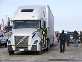 A police officer talks to a trucker at a roadblock on Highway 4 outside of Milk River heading towards the Coutts border crossing on Thursday, Feb. 3, 2022.