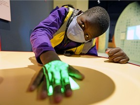 Daniel Dang, 8, meletakkan tangannya di bawah cahaya yang memungkinkan dia untuk melihat pembuluh darah di bawah kulitnya di Zona Kesehatan baru di Telus World of Science, Rabu, 2 Februari.  16, 2022.