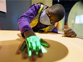 Daniel Dang, 8, meletakkan tangannya di bawah cahaya yang memungkinkan dia untuk melihat pembuluh darah di bawah kulitnya di Zona Kesehatan baru di Telus World of Science, Rabu, 2 Februari. 16, 2022.