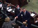 Premier Jason Kenney, left, applauds and other MLA's congratulate Finance Minister Travis Toews after delivering the 2022 Alberta budget in the chambers at the Alberta legislature in Edmonton on Thursday, Feb. 24, 2022. 