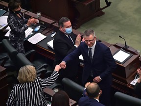 Premier Jason Kenney, left, applauds and other MLA's congratulate Finance Minister Travis Toews after delivering the 2022 Alberta budget in the chambers at the Alberta legislature in Edmonton on Thursday, Feb. 24, 2022.