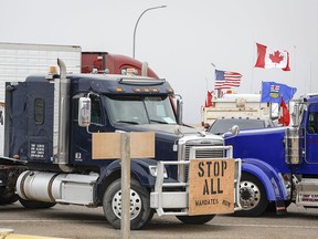 Anti-mandate demonstrators gather as a truck convoy blocks the highway at the U.S. border crossing in Coutts, Alta., Monday, Jan. 31, 2022.