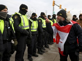 A protester gestures towards police officers, in Windsor who are starting to enforce a court order to clear truckers and supporters who have been protesting against coronavirus disease (COVID-19) vaccine mandates by blocking access to the Ambassador Bridge, which connects Detroit and Windsor, in Windsor, Ontario, February 12, 2022. REUTERS/Carlos Osorio