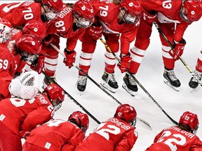 Russia's Olympic Committee players wearing protective masks react before the women's preliminary round group A match of the Beijing 2022 Winter Olympic Games ice hockey competition players of Russia's Olympic Committee and Canada.