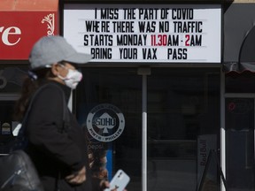 A pedestrian makes their way past a COVID-19 sign outside SOHO, 11454 Jasper Ave., in Edmonton Thursday Sept. 23, 2021.